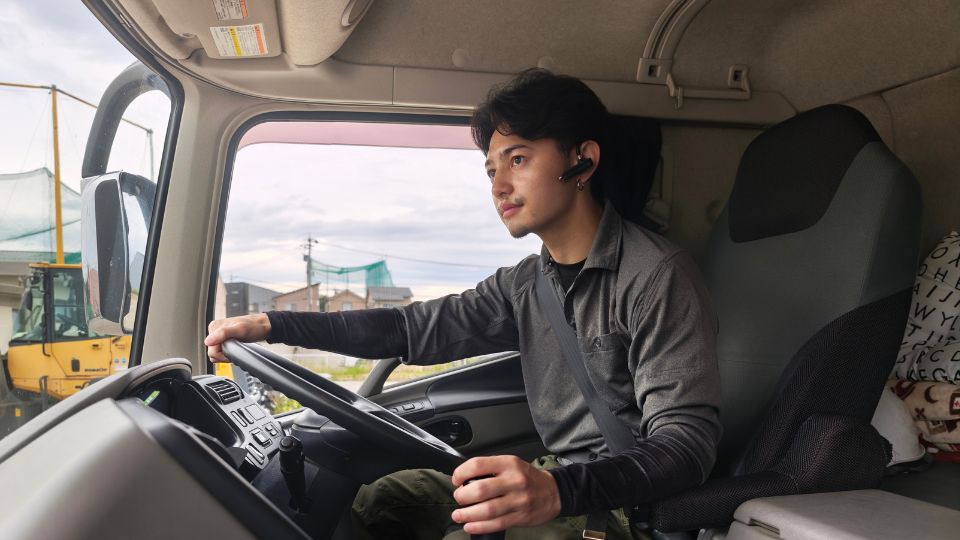 真剣な眼差しでハンドルを握るシンメ建設運輸の若い運転手大型ドライバー越村郁人（20代）