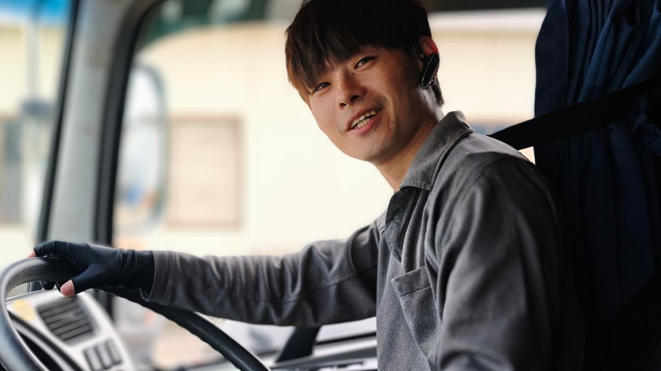 仕事へのやりがいを語るシンメ建設運輸の大型運転手、笑顔で運転席に座る内海涼（20代）